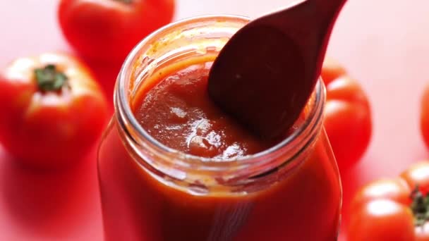 Томатный соус в маленькой банке со свежими помидорами на столе — стоковое видео