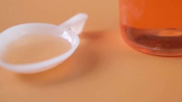 Frasco com medicamento líquido sobre fundo laranja — Vídeo de Stock