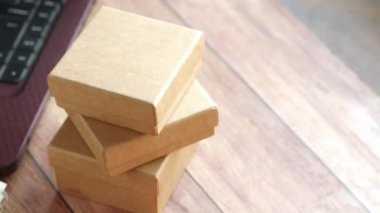 Masada bir yığın karton paket ve laptop var. 