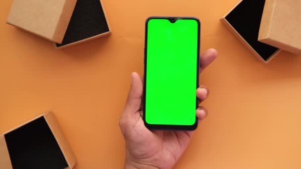Ansicht von oben mit Smartphone und leerer Box auf orangefarbenem Hintergrund — Stockvideo