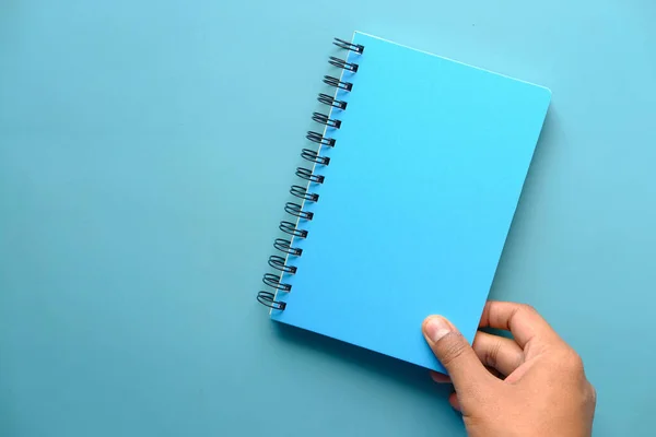 Tenant le bloc-notes de couleur bleue sur fond de couleur — Photo