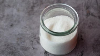 Siyah arkaplanda cam kavanozda beyaz şeker 