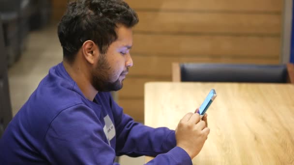 Молодий чоловік рука за допомогою смартфона, що сидить на столі в кафе — стокове відео
