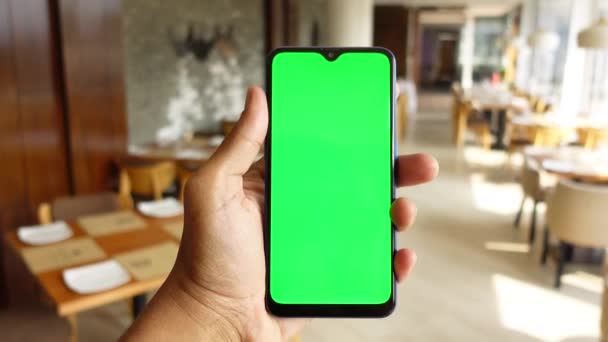 Mano de hombre joven utilizando el teléfono inteligente con pantalla verde en la cafetería — Vídeos de Stock