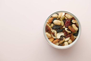 Açık mor arka planda bir kasede karışık fındıkların üst görüntüsü 