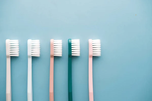 Colorful toothbrushes on light green background with copy space — Stock Photo, Image