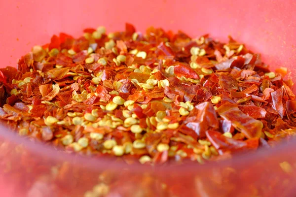 Primer plano de copos de chile rojo en un tazón en rojo — Foto de Stock