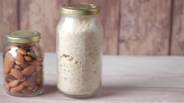 Masadaki kavanozda badem tozu ve badem.,