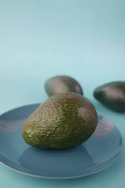 Skiva av avokado på en platta på ljusgrön bakgrund — Stockfoto