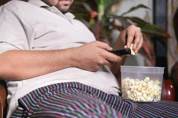 Junger Mann isst Popcorn und hält Popcorn auf Sofa — Stockfoto