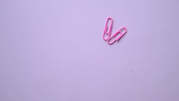 Clipe de papel colorido caindo no fundo rosa . — Vídeo de Stock