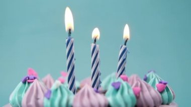 Açık mor arkaplanda doğum günü pastasında yanan mumun yavaş çekimi 