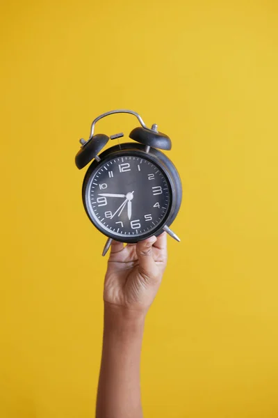 Reloj despertador de mano persona sosteniendo sobre fondo amarillo , —  Fotos de Stock