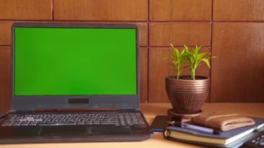 Ofis masasında yeşil ekranlı bir laptop..
