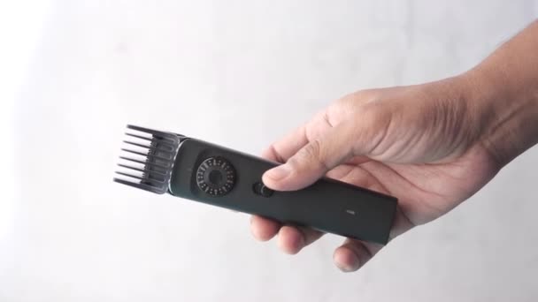 Sosteniendo un cortador de pelo sobre fondo blanco — Vídeos de Stock