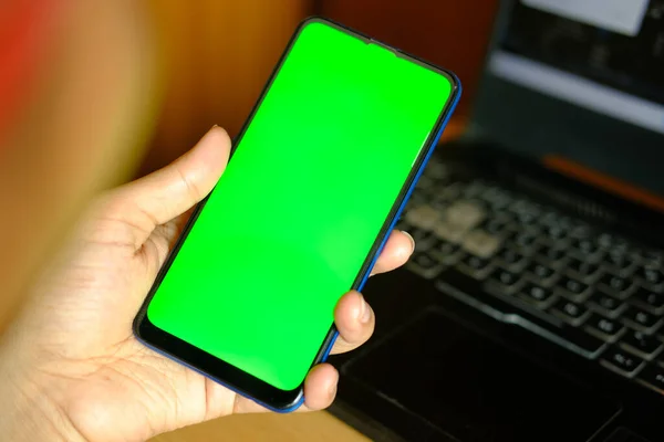 Nahaufnahme der Hand eines jungen Mannes mit Smartphone mit grünem Bildschirm — Stockfoto