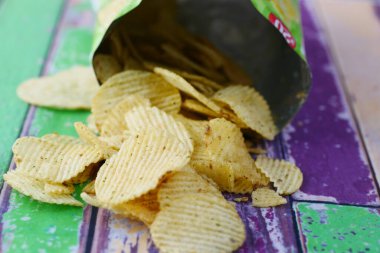 Elinde açık patates cipsi paketi var. 