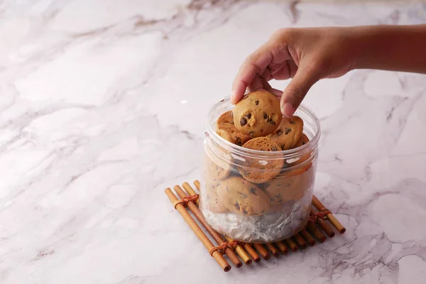 Hand plukken zoete koekjes uit een plastic pot — Stockfoto