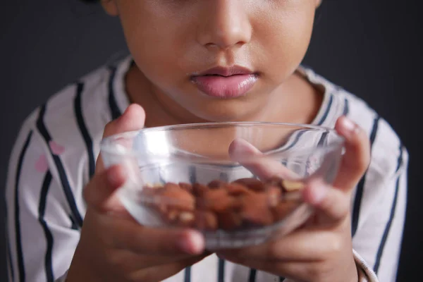 Kid hand holding a bowl of almond on black — Stock Photo, Image