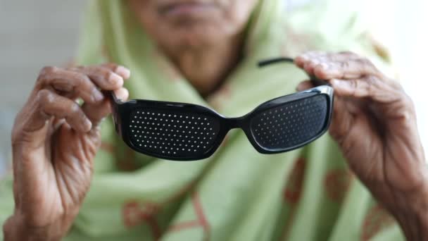 Asiatische Seniorinnen vergolden Perforationsbrille mit Löchern für das Sehtraining — Stockvideo