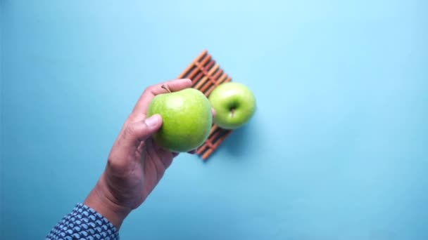 Main tenant pomme verte sur fond bleu — Video