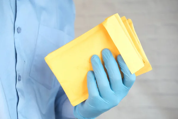 Hand in hand latex handschoenen met gele papieren bubbel envelop voor postschip. — Stockfoto