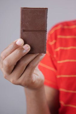  çocuk eli ile siyah çikolatayı gri arka planda seçer 