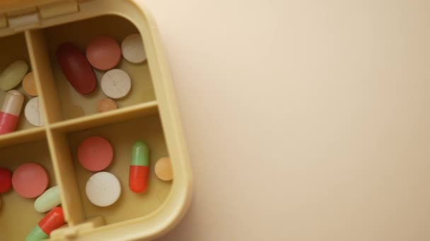 Vista superior de las píldoras médicas en una caja de pastillas sobre fondo de color — Vídeos de Stock