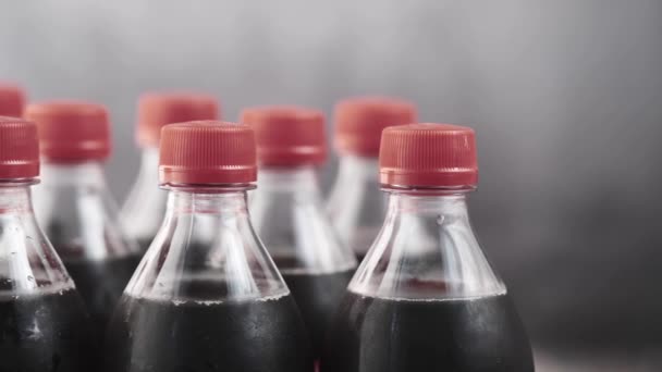 Пластиковые бутылки безалкогольных напитков с красной крышкой на столе — стоковое видео