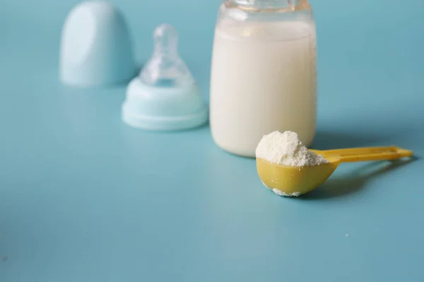 Zbliżenie mleka w proszku dla niemowląt i łyżki na tle płytek. — Zdjęcie stockowe