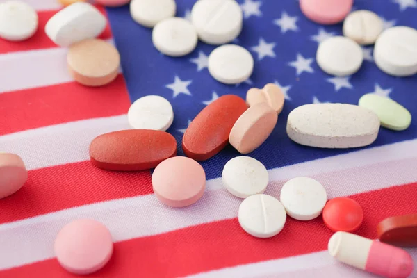 Медицинские таблетки белого цвета, разливающиеся на американский флаг — стоковое фото