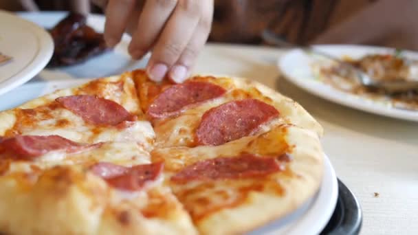 Handplockning skiva pepperoni pizza på en tallrik — Stockvideo