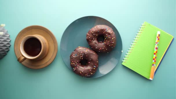 Pączki czekoladowe, herbata i notatnik na stole — Wideo stockowe