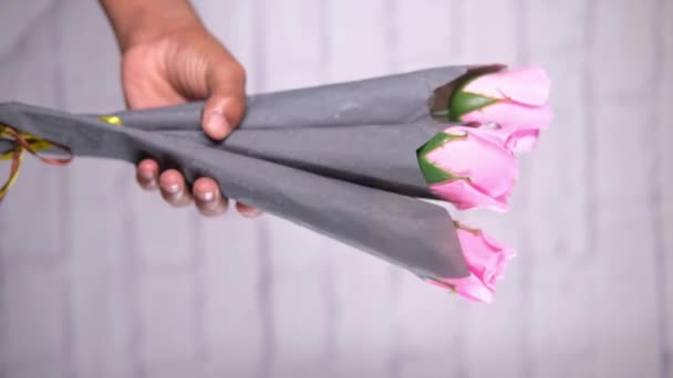 Hand holding rose flower against white wall — Stock Video