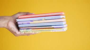 Renkli arkaplan üzerine el ele kitap yığını 