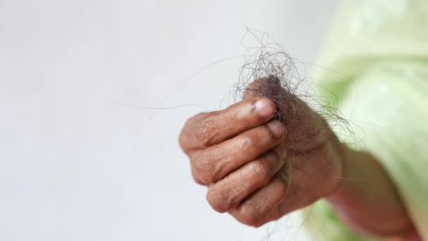 Senior kvinnor hand hålla en borste med förlorat hår på vit bakgrund — Stockvideo