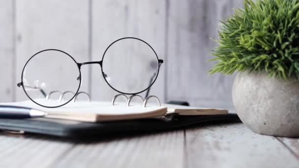 Open boek, mok, bril en potlood op houten tafel — Stockvideo