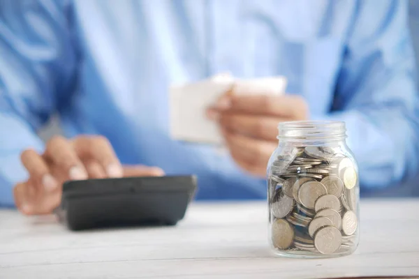 Young man saving coins in a jar white sited — Stock Photo, Image