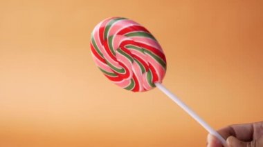 Lolipop şekerini turuncu arka planda tutma 