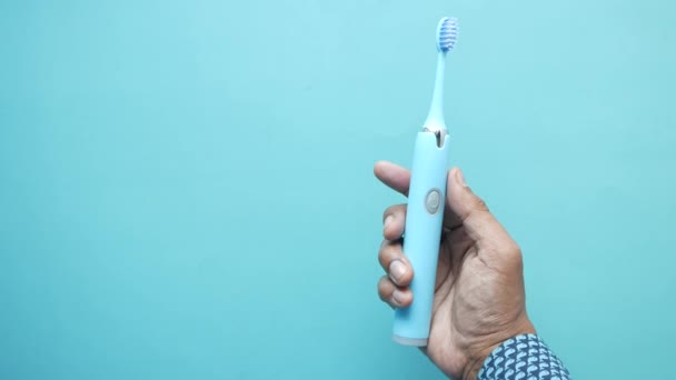Memegang warna biru sikat gigi elektronik — Stok Video