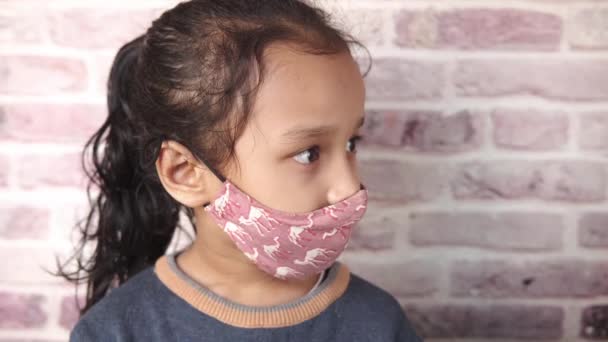 Een boos kind meisje met gezichtsmasker kijken weg — Stockvideo