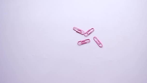 Clipe de papel colorido caindo no fundo rosa . — Vídeo de Stock