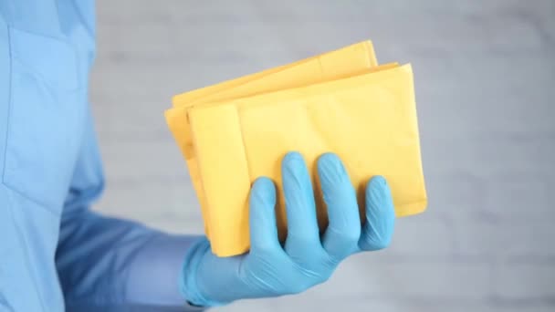 Hand in latex gloves holding white paper bubble envelope for postal ship. — Stock Video