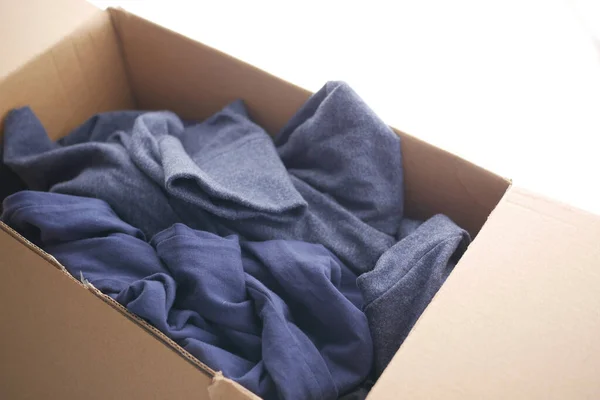Коробка для пожертвований с одеждой для пожертвований на деревянном столе . — стоковое фото
