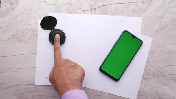 Verschillende zwarte vingerafdrukken op een papier met smartphone op tafel — Stockvideo