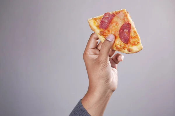 Uomo mano raccogliendo fetta di pizza contro sfondo bianco — Foto Stock