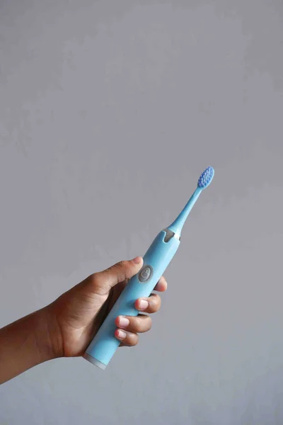 Sosteniendo un cepillo electrónico de color azul — Foto de Stock