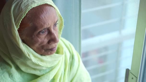 Ledsna asiatiska äldre kvinnor tittar genom fönstret — Stockvideo