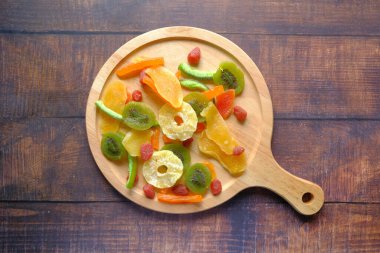 Masadaki tahtanın üzerinde kurumuş meyve ve böğürtlen var. 