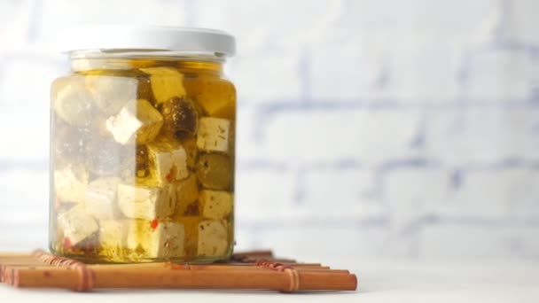 Cubo de queso, aceitunas y hierbas en un recipiente sobre la mesa — Vídeos de Stock